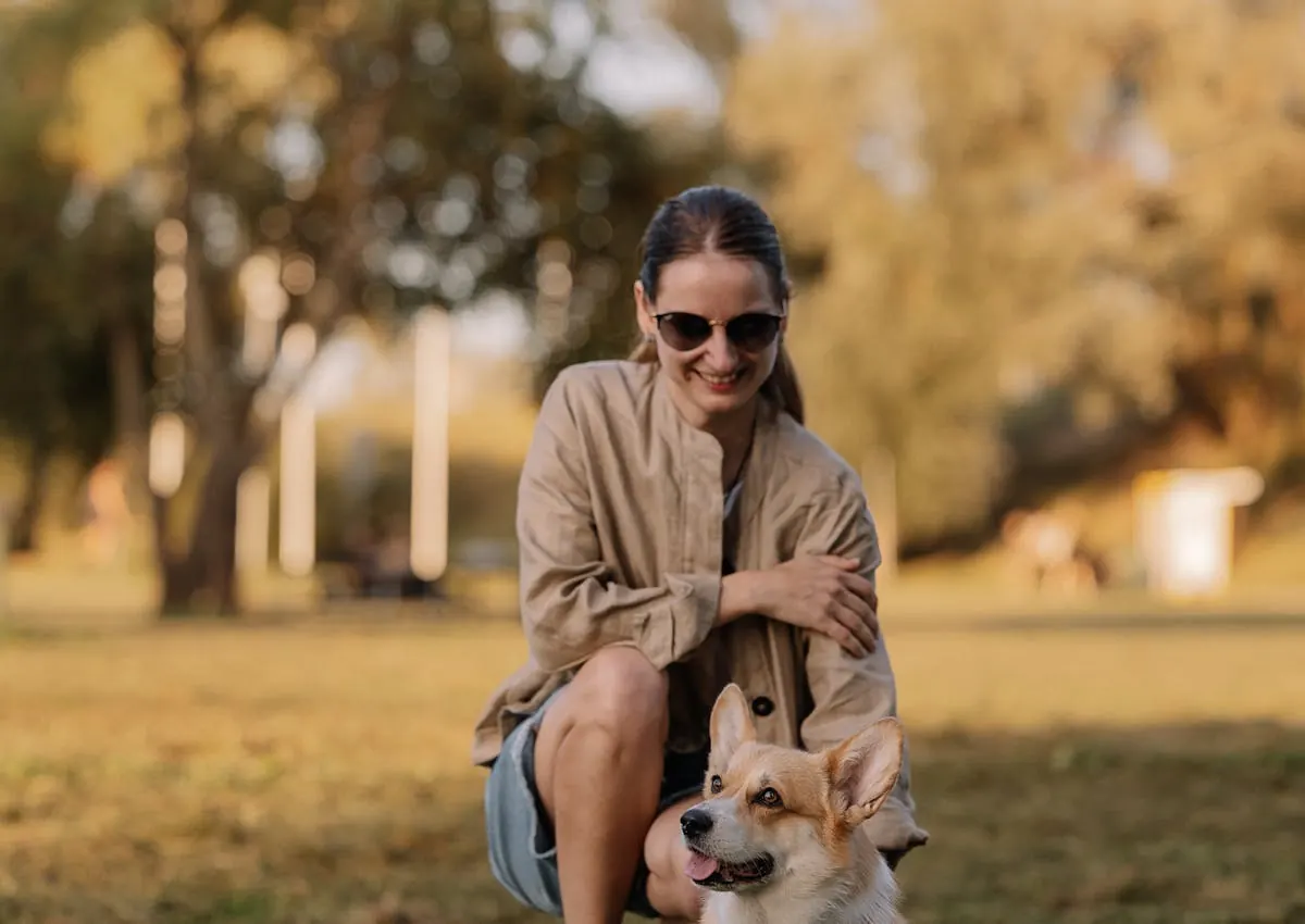 Dog owner sitting with a corgi in a park
