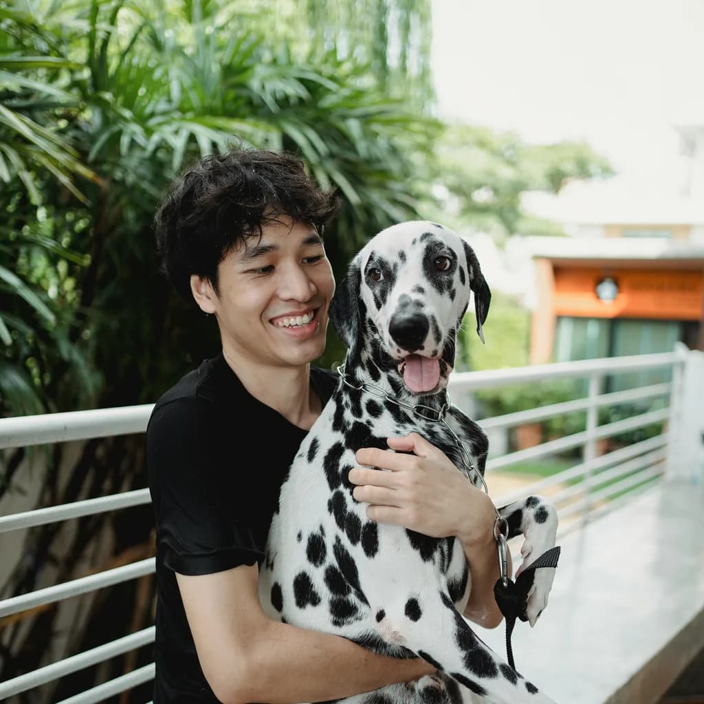 Young dog owner holding a Dalmatian outdoors in a testimonial-style portrait